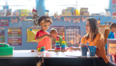 A preschool girl is actively learning and growing under the guidance of her teacher in a nurturing daycare environment